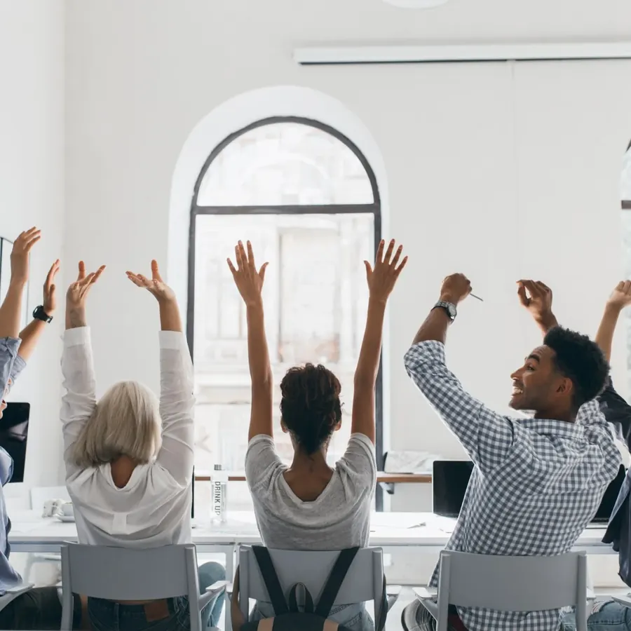 Colleagues in a bright office raising their arms in celebration